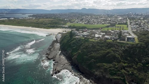 Aerial orbit around cliffside homes and exposed rocks along tidal shelf in Port Kembla NSW Australia photo