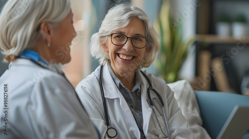 Happy doctor together with senior patient having fun at medical checkup at clinic. Smiling old woman and friendly physician sitting on medical couch looking at good analysis result