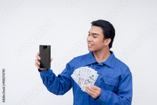 Fotografie A cheerful construction worker holding both cash and a smartphone, representing mobile remittances or online banking services