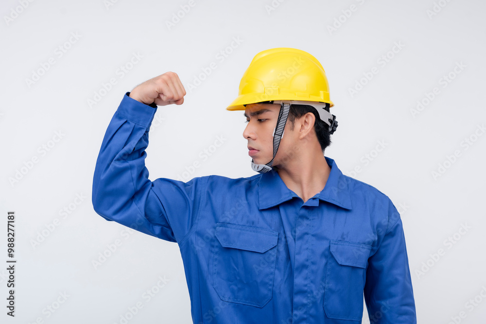 A young construction worker in blue coveralls flexes his arm confidently, wearing a yellow hard hat. Isolated on a white background, showcasing strength and dependability. A young construction worker in blue coveralls flexes his arm confidently, wearing a yellow hard hat. Isolated on a white background, showcasing strength and dependability.