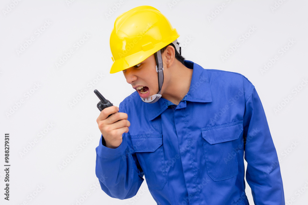 A young construction worker in blue coveralls angrily yelling into a two-way radio, conveying urgency and frustration. Isolated on a white background, emphasizing communication and management stress. A young construction worker in blue coveralls angrily yelling into a two-way radio, conveying urgency and frustration. Isolated on a white background, emphasizing communication and management stress.