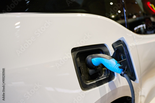 Close-up of electric vehicle charging at station. EV car with plugged-in cable recharging battery. Clean energy transportation photo