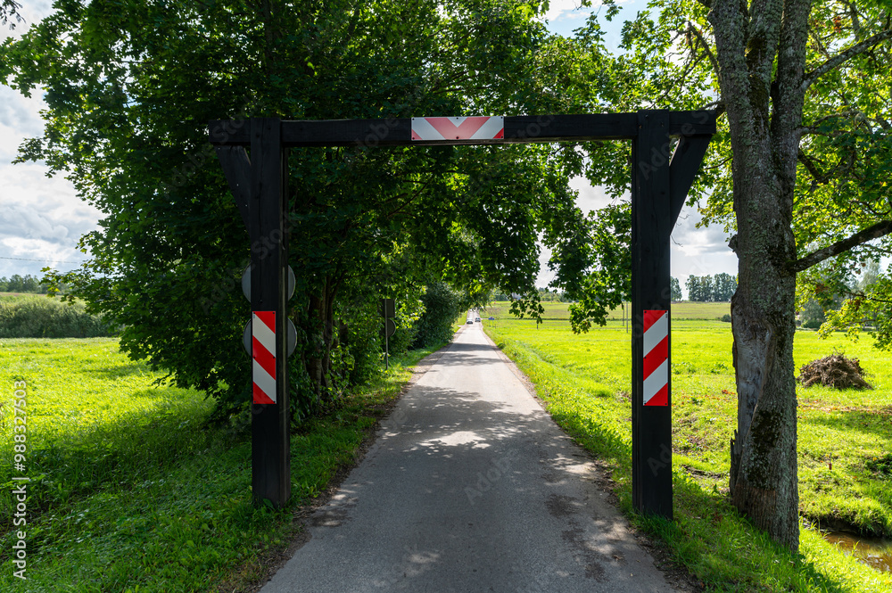 A picturesque rural path framed by a wooden gateway under a clear sky on a sunny day A picturesque rural path framed by a wooden gateway under a clear sky on a sunny day