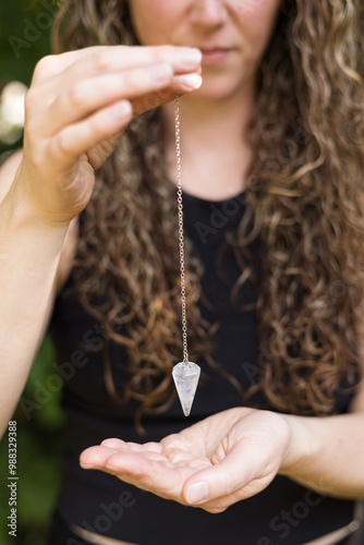 Close up of woman Reiki master holding crystal pedulum over hand photo