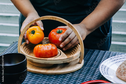 African American woman places heirloom tomatoes in a basket photo