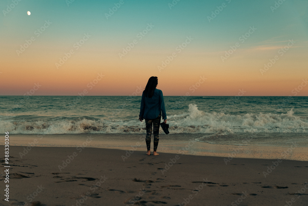 Woman contemplates the calm of the sea with the moon in the distance. Woman contemplates the calm of the sea with the moon in the distance.