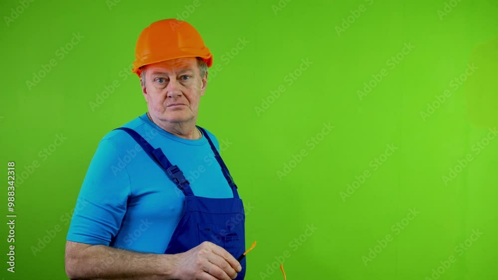 Senior worker in overalls and helmet and protective glasses looking at camera and smiling. Senior worker in overalls and helmet and protective glasses looking at camera and smiling.