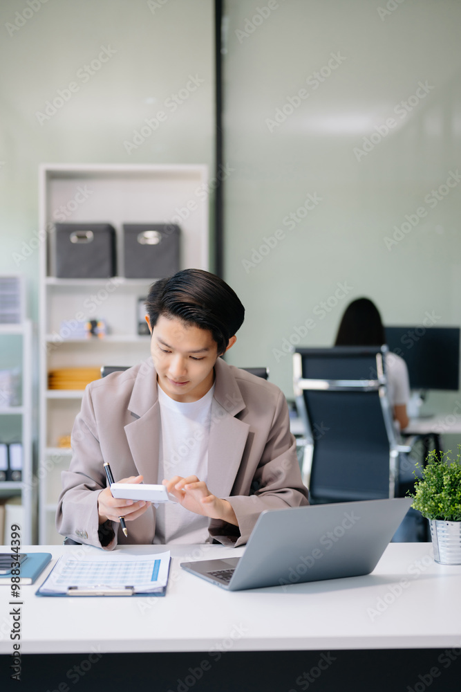 Young businessman working with laptop, tablet and taking notes on the paper at office.. Young businessman working with laptop, tablet and taking notes on the paper at office..