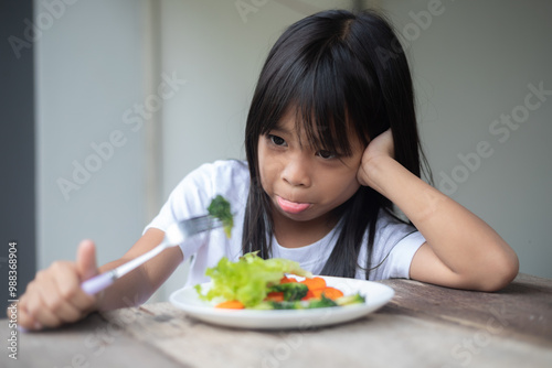 A young girl is eating a salad with a fork.