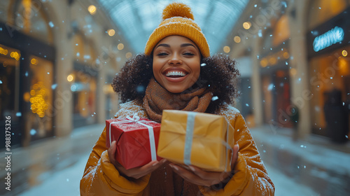 Smiling Black woman holding Christmas presents in snowy outdoor shopping mall, festive holiday mood