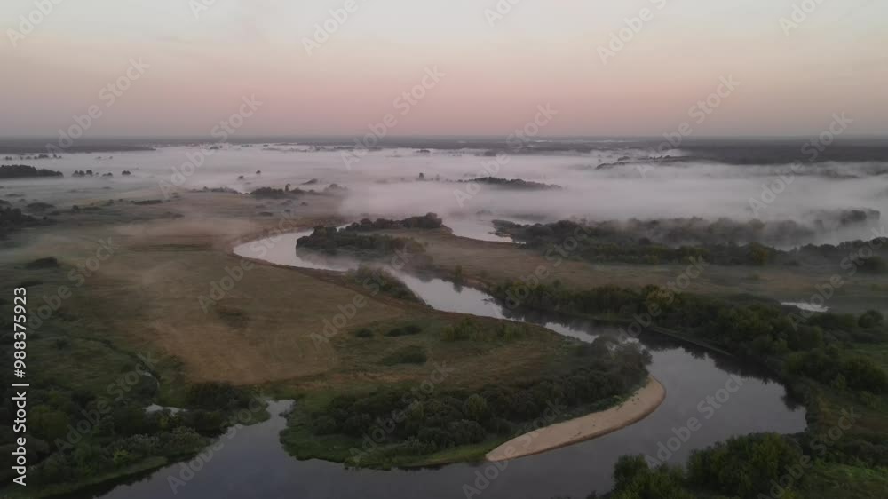 Morning fog begins to creep along the winding river among meadows, fields and forests. In the morning before sunrise. Morning fog begins to creep along the winding river among meadows, fields and forests. In the morning before sunrise.