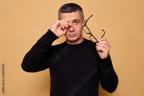 Fotografía Unwell Caucasian overworked man wearing black raglan taking off glasses rubbing