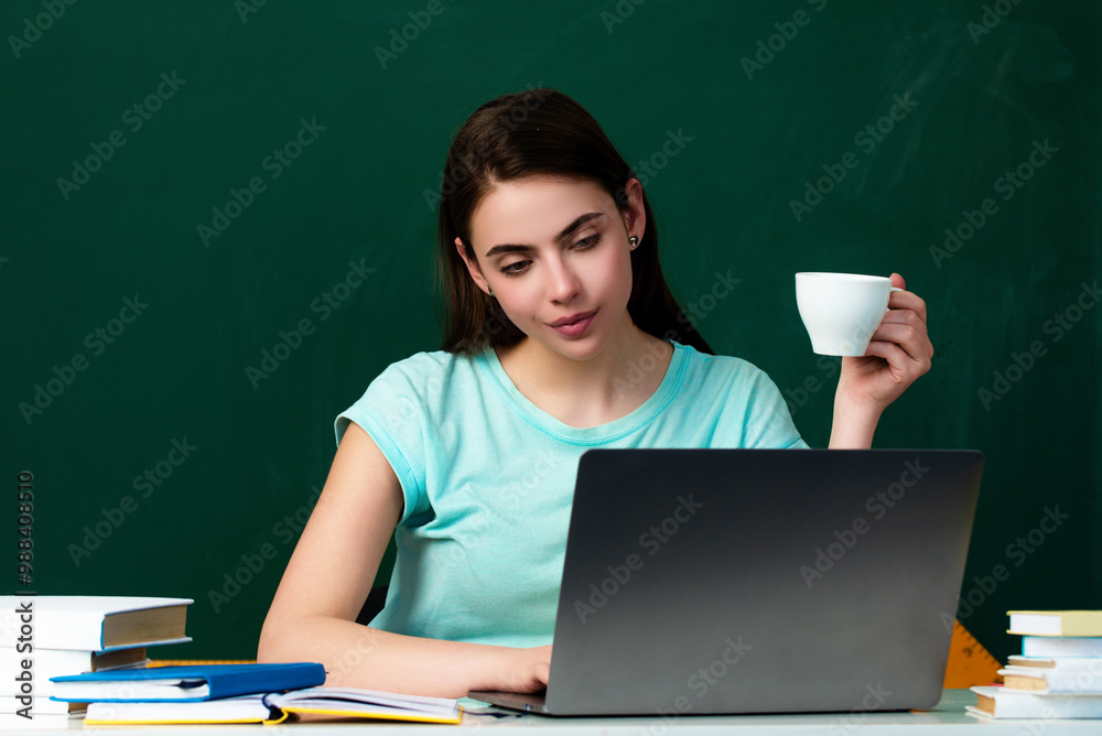 The student girl is studying in the classroom. The student girl works hard to understand the material. Student drinking coffee in classroom. Coffee break in university. Student girl hold coffee cup. The student girl is studying in the classroom. The student girl works hard to understand the material. Student drinking coffee in classroom. Coffee break in university. Student girl hold coffee cup.