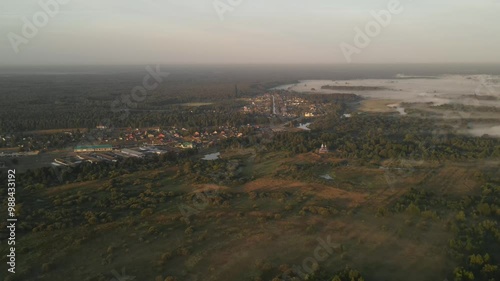 The concept of living in an ecologically clean place surrounded by forests meadows and lakes. A drone video capturing a spring landscape in the fog. Top view of the earth at dawn