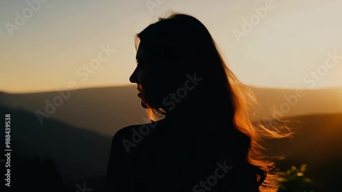 Silhouette of woman at sunset with flowing hair and mountain view