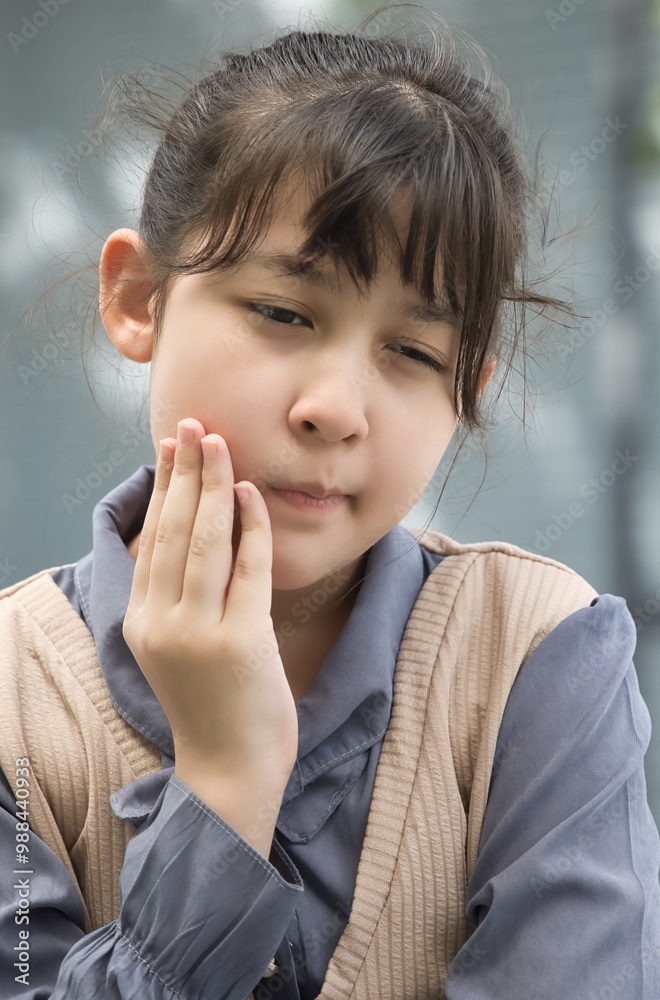 Little Asian primary schooler girl suffering from toothache, tooth decay, tooth sensitivity, wisdom tooth pain, cavity, dental care concept Little Asian primary schooler girl suffering from toothache, tooth decay, tooth sensitivity, wisdom tooth pain, cavity, dental care concept