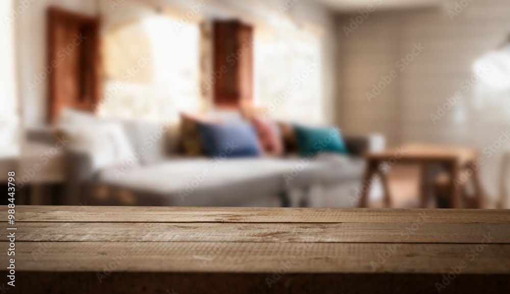 A wooden table top with a blurred background of a living room. A wooden table top with a blurred background of a living room.