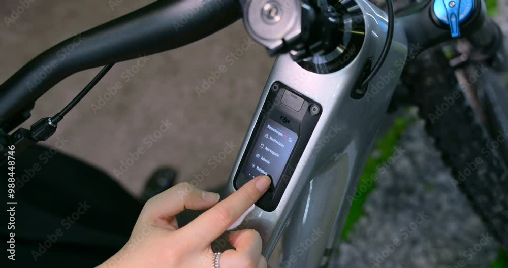 Close-up of a person using the control display on an electric bike to navigate through settings and menu options.