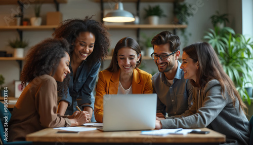 Smiling Diverse Group of Young Business Professionals Meeting and Looking at Laptop During Business Presentation in Cafe or Coffee Shop