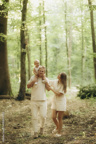 Child embrace parents happiness playing in green grass in park. Happy mother, father hug baby son walking in garden at sunset. Family spending time together outdoors. Children's day. Friendly family.