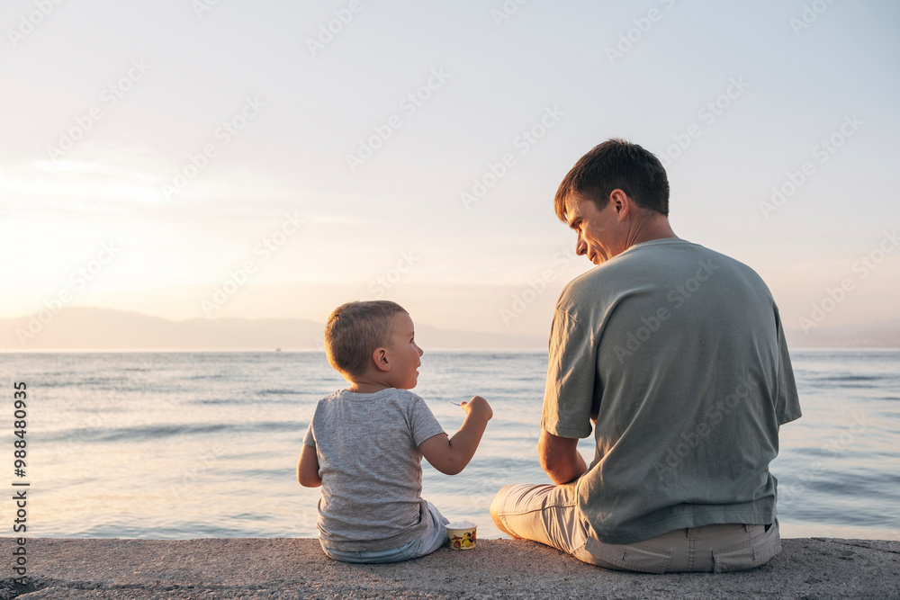 Father and son sitting on seashore Father and son sitting on seashore