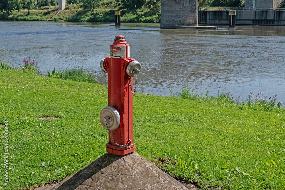 Red-coloured fire hydrants on the riverside.