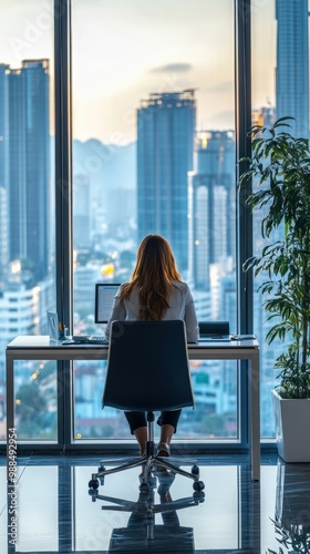 A businesswoman in a sleek modern office, sitting at her desk with large glass windows behind her, offering a panoramic cityscape photo