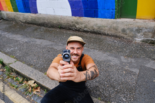 Gay man holding camera and sitting in street photo