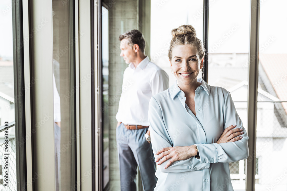 Happy businesswoman with colleague standing in background Happy businesswoman with colleague standing in background