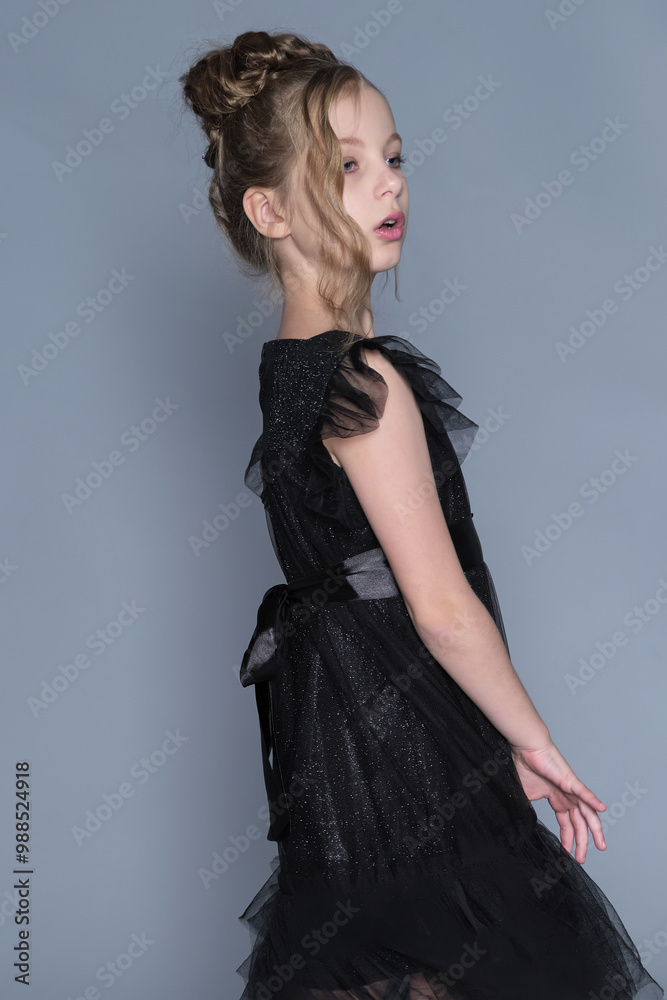 Fototapeta premium A girl gently lifts the sides of her black dress, showing off the dress's sheer layers and ruffled design. The scene emphasizes grace and confidence, showcasing the intersection of fashion and