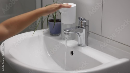 A faucet with running water. Water tap made of chrome material. Kid turns off the water
