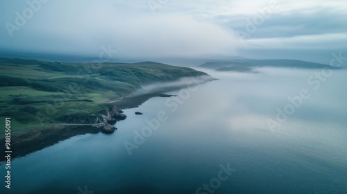 A serene coastal scene with misty hills and calm waters blending into the fog.