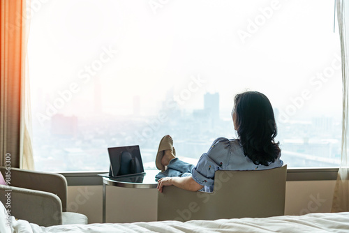 Work-Life balance, life quality, work and travel concept with business woman relaxing sitting in rest, take it easy in modern hotel guest room or luxury home living room with notebook and city view