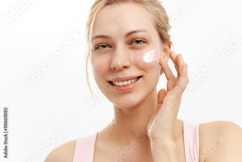 Smiling woman applying cream on her face, protection. Cream protects skin from photoaging and harmful effects ultraviolet rays.