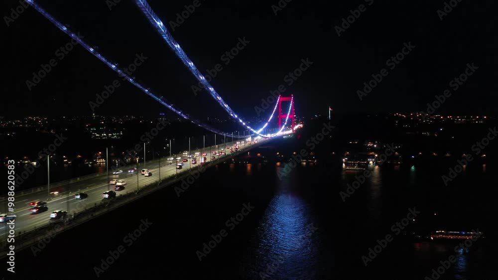 Nighttime Aerial Drone Footage of Fatih Sultan Mehmet Bridge Illuminated Over the Bosphorus in Istanbul with City Lights and Traffic Below