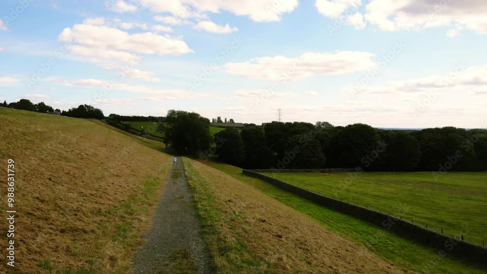 Woman walking on pathway through fields Woman walking on pathway through fields