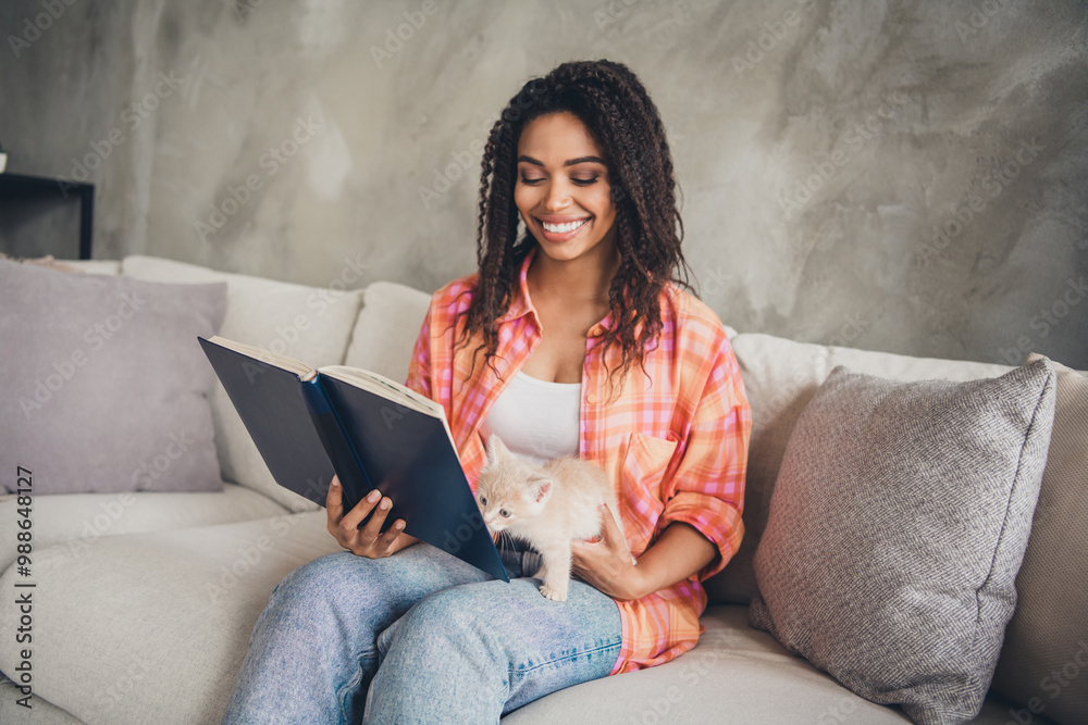 Photo of positive good mood woman dressed checkered shirt reading novel play baby cat indoors house apartment room Photo of positive good mood woman dressed checkered shirt reading novel play baby cat indoors house apartment room