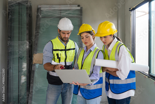 Bild auf Leinwand Young architect pointing at laptop computer monitor explain to foreman and engineer about a floor plan