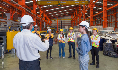 Warehouse safety meeting, people with hard hats. Industrial teamwork.