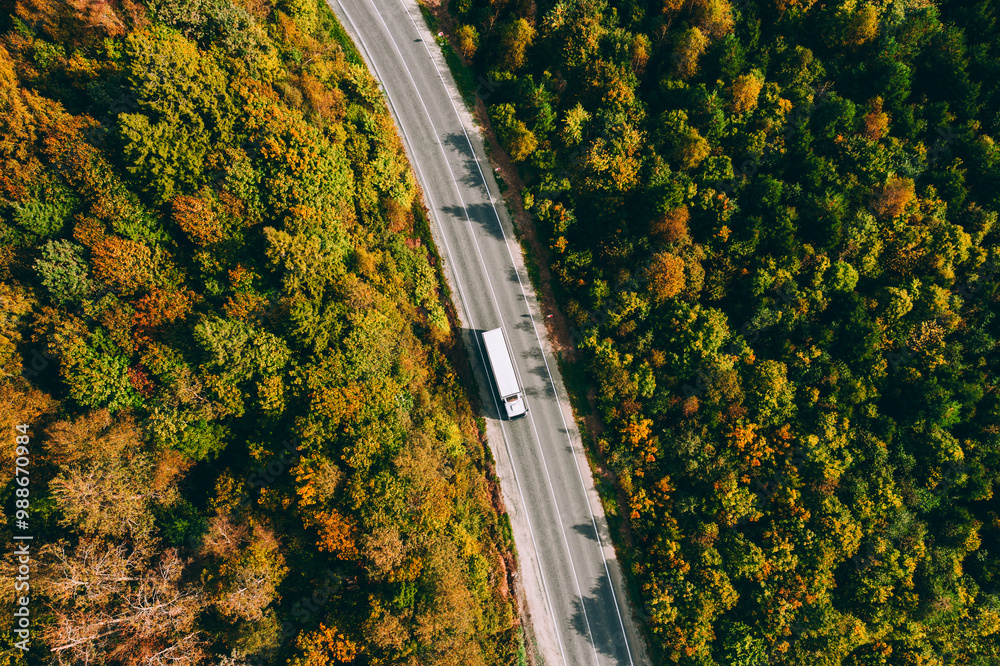 Aerial view of truck car driving on asphalt road in fall autumn color forest