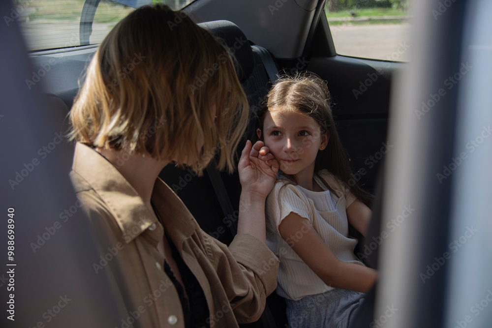 A mother with her daughter in the backseat of a car A mother with her daughter in the backseat of a car