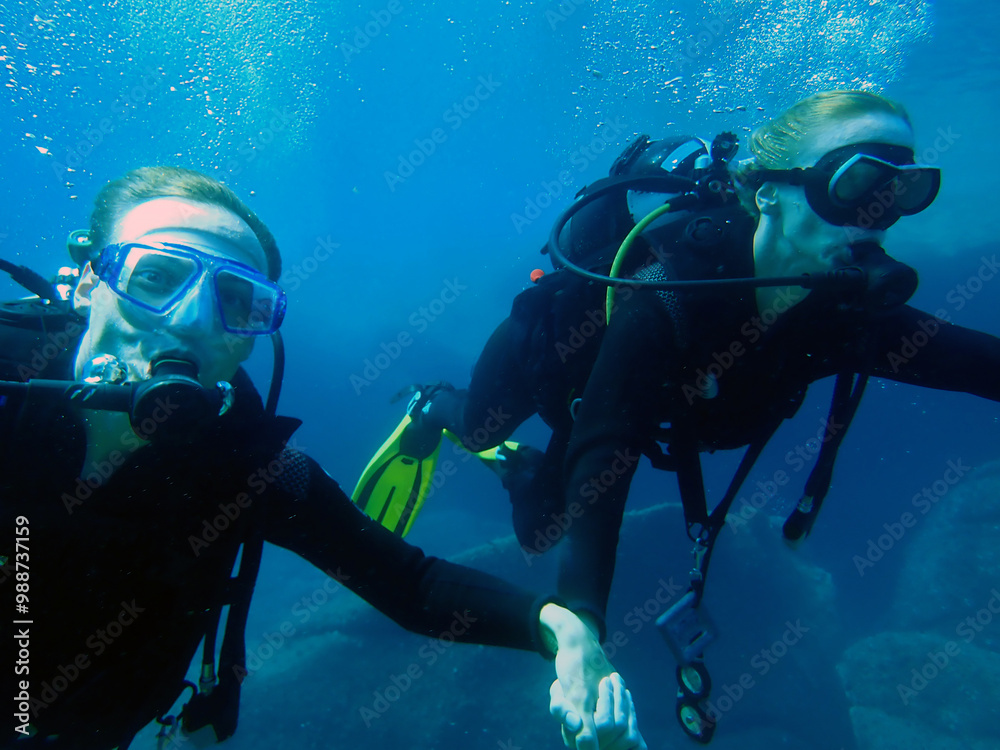 Two divers explore a thrilling underwater adventure in the clear blue ocean Two divers explore a thrilling underwater adventure in the clear blue ocean