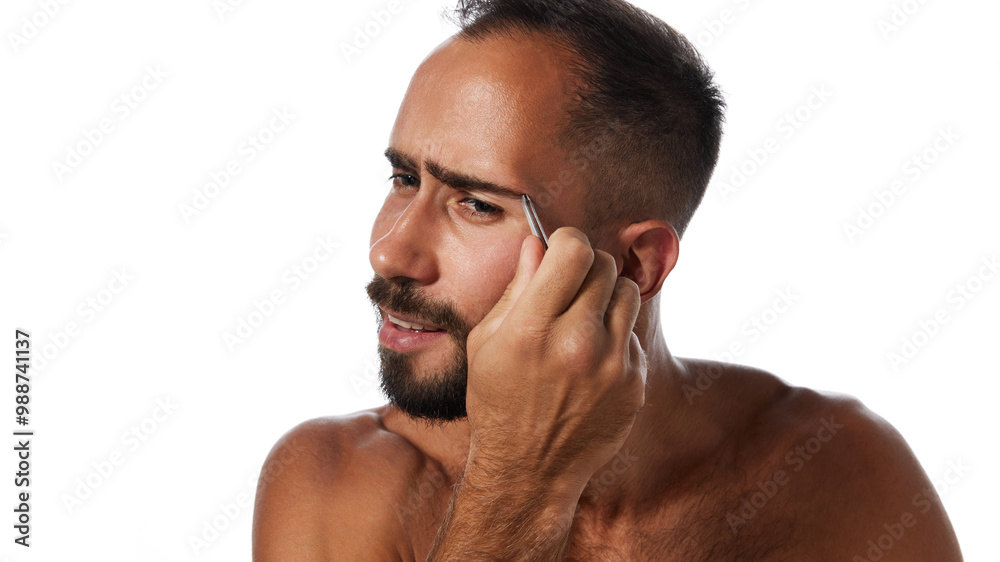 Obraz premium Portrait of handsome young bearded man taking care after his appearance, using tweezers, plucking eyebrows isolated on white background. Concept of male beauty, skin care, hygiene, health, cosmetics