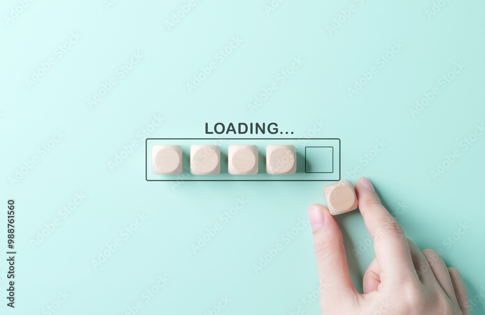 Loading bar concept. Progress bar, A hand placing a wooden block into a loading bar made of blocks, set against a mint green background, representing progress, patience, update, or waiting. Loading bar concept. Progress bar, A hand placing a wooden block into a loading bar made of blocks, set against a mint green background, representing progress, patience, update, or waiting.
