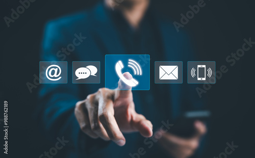 Customer Service Call Center, Contact US, Care Support Hotline, Hand touches glowing digital phone icon among various communication symbols, representing customer service and multiple contact methods.