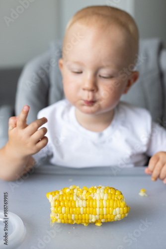 Toddler boy enjoying eating sweet corn cob. Selective focus.  photo