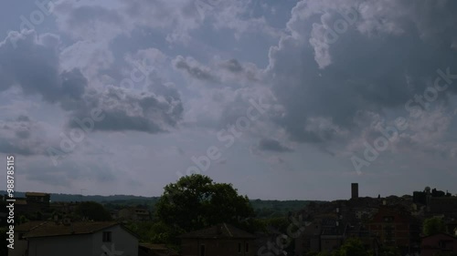 timelapse of the movement of floating clouds over hills and a tower