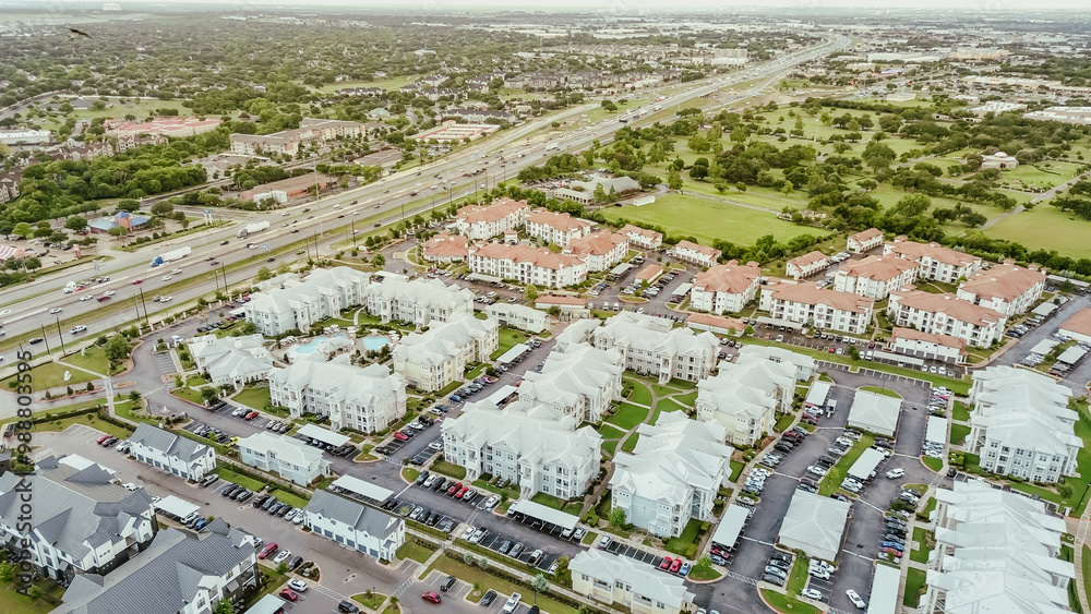 Fototapeta premium Interstate I-35 busy traffic in northeast of downtown Austin, Texas near colorful painted new apartment complex metal roofings, busy outdoor parking, rental community, housing market, aerial