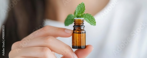 Person holding a small bottle of peppermint essential oil, inhaling its refreshing scent   peppermint oil, aromatherapy benefits
