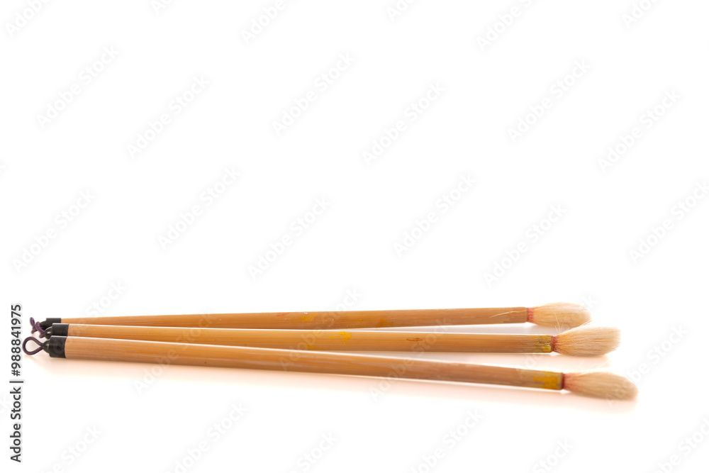 Three artistic paintbrushes arranged on a bright surface during daylight hours, representing creativity in a studio environment Three artistic paintbrushes arranged on a bright surface during daylight hours, representing creativity in a studio environment